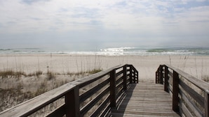 A wooden boardwalk leading to a beach with sand and sparse vegetation. - Shipwatch A403 (Pensacola)