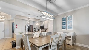 A modern kitchen with white cabinetry, a wooden dining table, and pendant lighting. - Lost Key B304 (Pensacola)