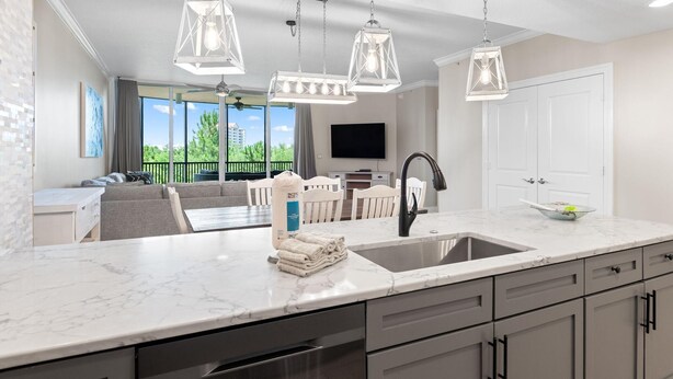A modern kitchen with a large island, pendant lighting, and a view to the outdoors. - Lost Key B304 (Pensacola)