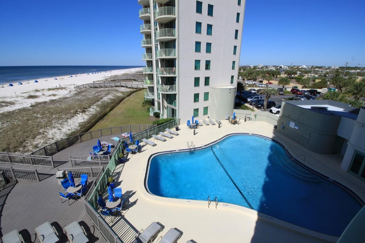 A hotel with a pool, beach view, and a parking area.