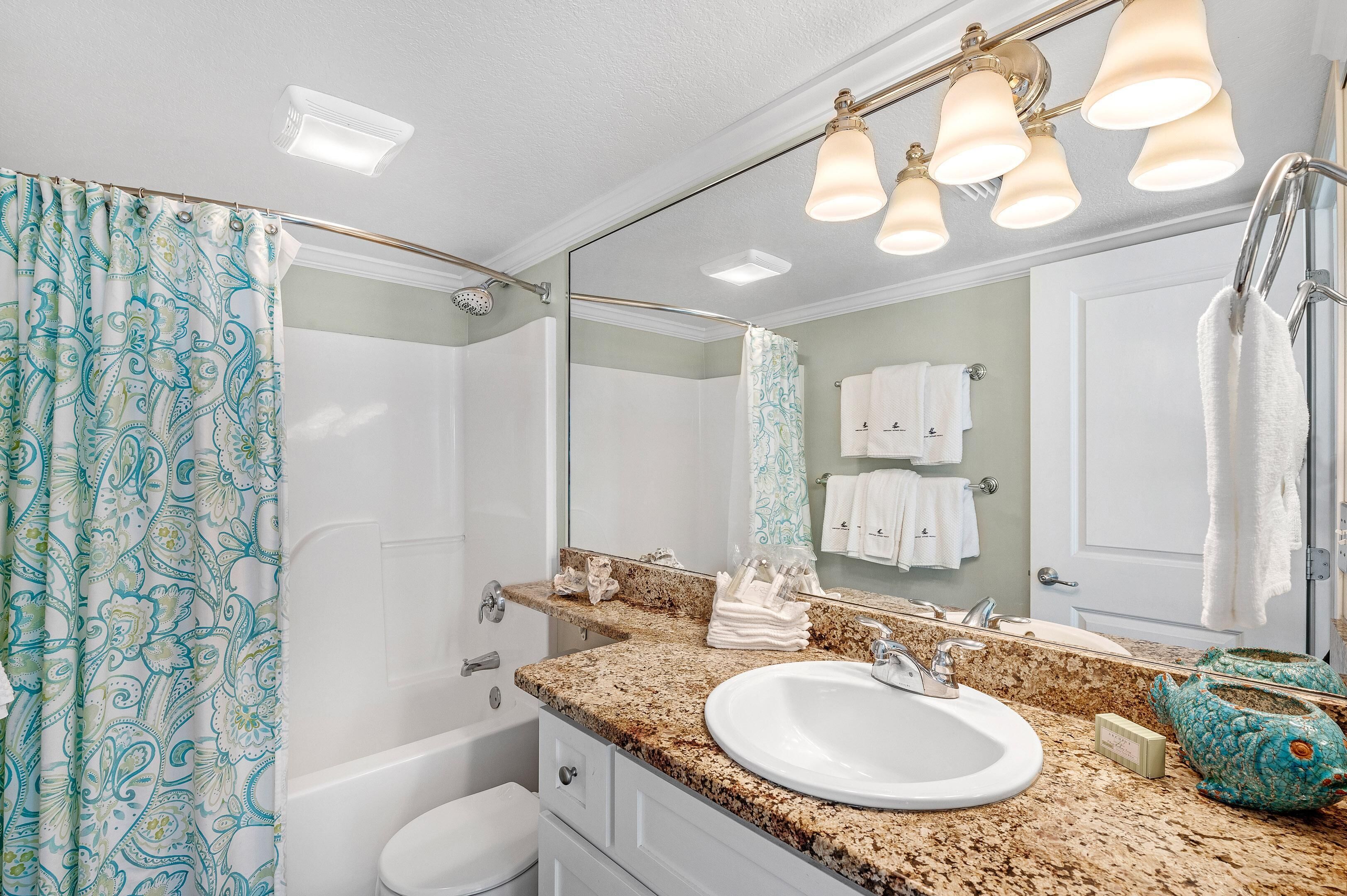 A bathroom with a sink, mirror, towel rack, and shower curtain.