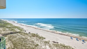 Blick auf einen Strand mit klarem Himmel, Sand und einigen Sonnenschirmen.