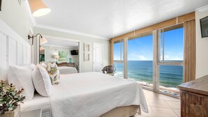 Ein Schlafzimmer mit einem großen Bett, Meerblick und einer Schiebetür zu einem Balkon.