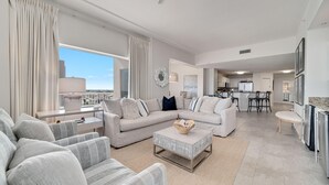 A spacious living room with a large sectional sofa, a coffee table, and a view of the city. - Spanish Key 510 (Pensacola)