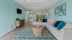 A living room with a sofa, coffee table, and artwork on the walls. - Shipwatch Riverside E1005 (Pensacola)