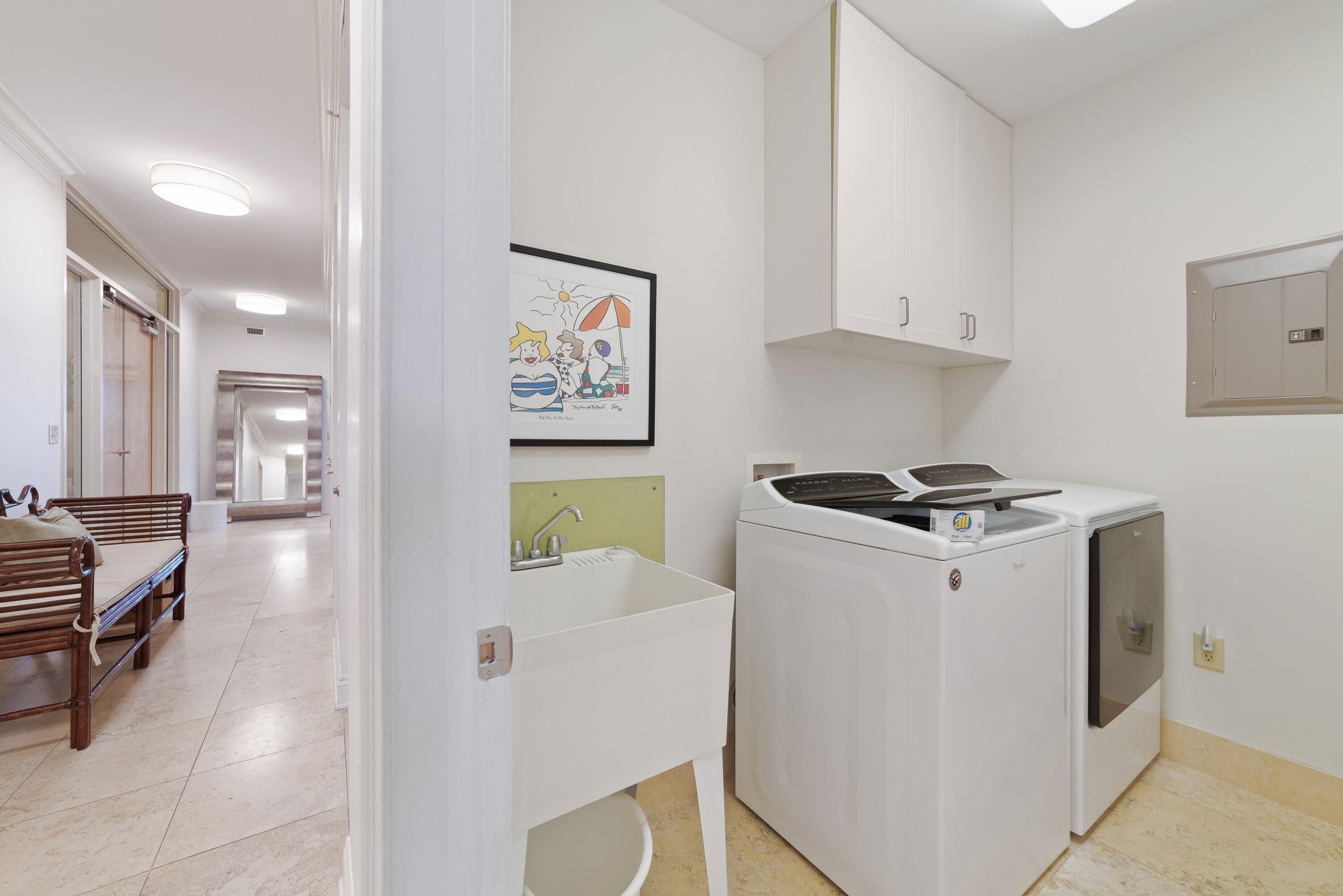 A compact kitchen with a washing machine, a sink, and cabinets.