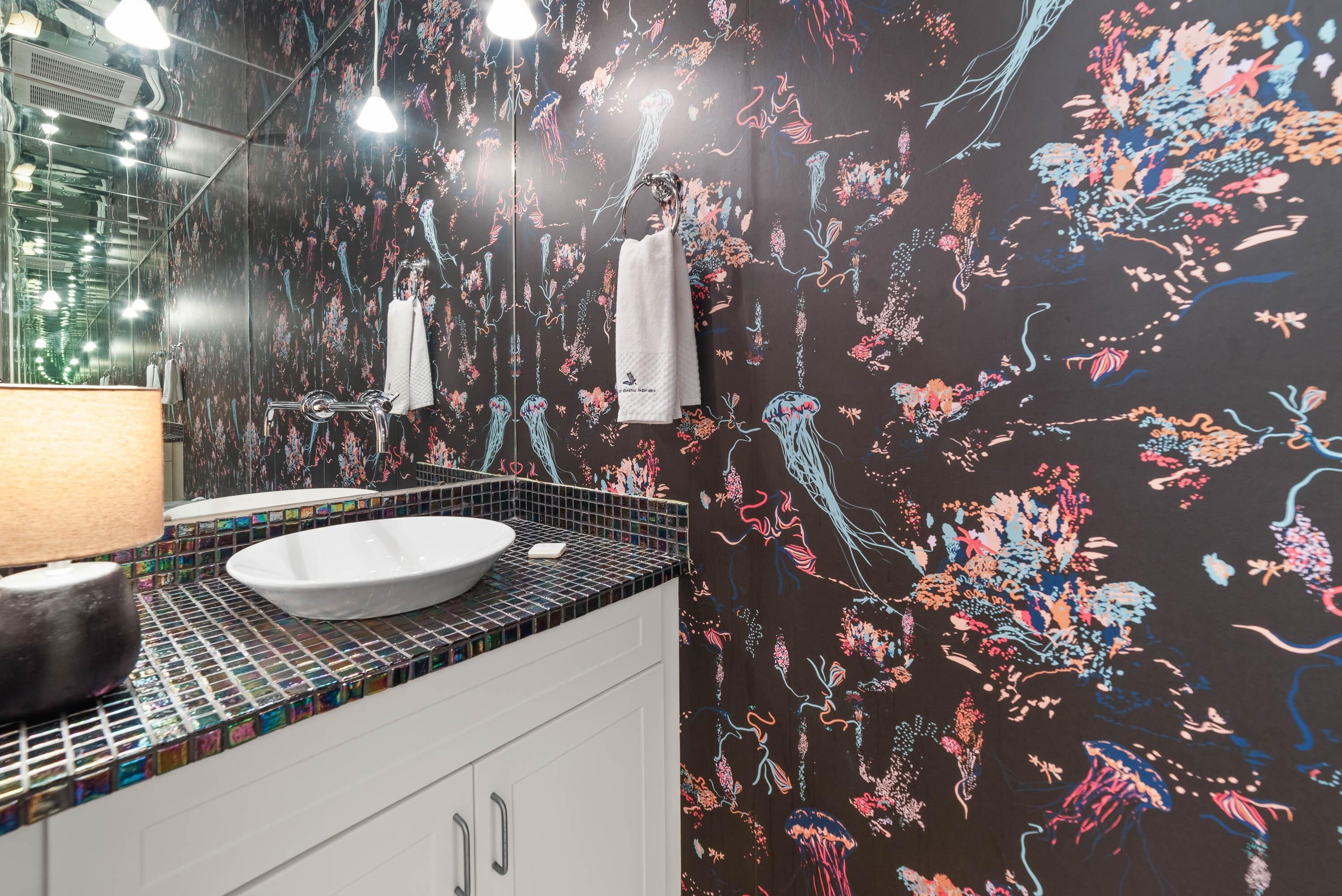 A bathroom with a white sink, a mirror, and a tiled backsplash.
