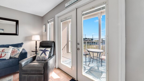 Ein Zimmer mit Ledersessel, einem kleinen Tisch und Blick auf einen Balkon mit Gartenmöbeln.