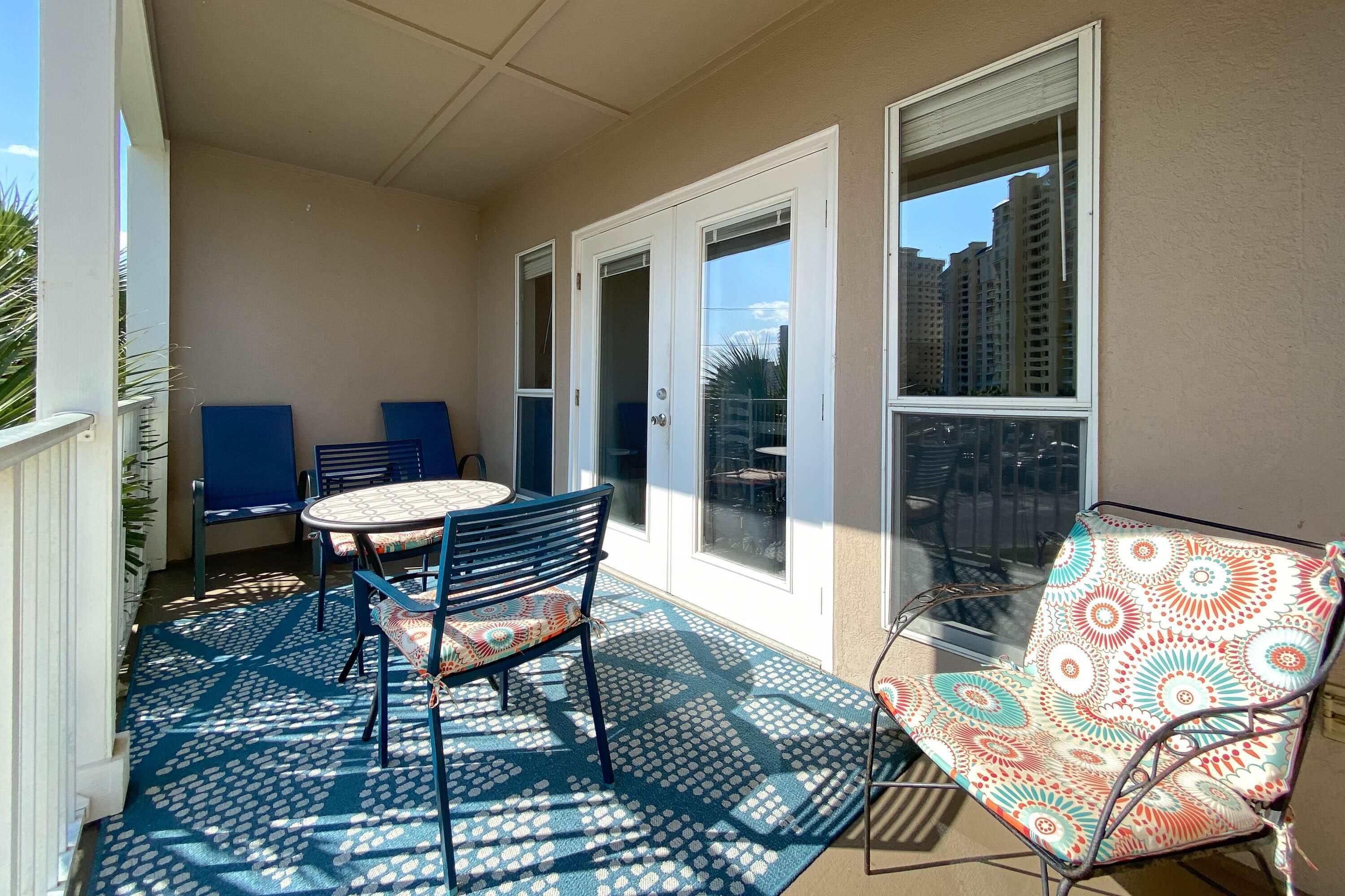 Ein Balkon mit Tisch und Stühlen, einem gemusterten Teppich und Blick auf hohe Gebäude.