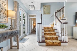 A staircase with white balusters and a wooden handrail, leading to a landing with a patterned carpet.