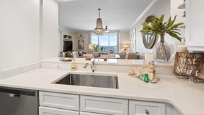 Una cucina moderna con una grande isola, lavello in acciaio inossidabile e vista sull'area living.