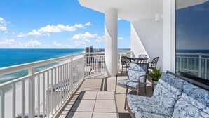 A balcony with a view of the ocean, white railings, and a seating area with patterned cushions. - Palacio 1804 (Pensacola)