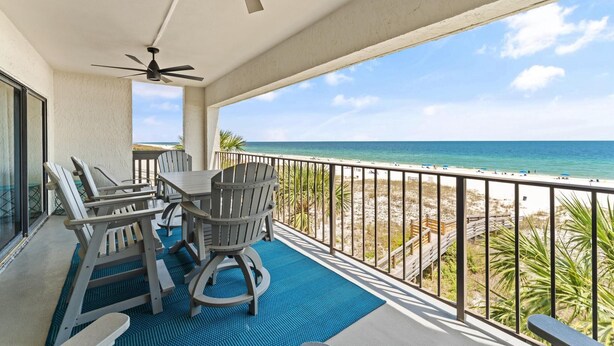 A balcony with a table and chairs, a ceiling fan, and a view of the beach. - Shipwatch D401 (Pensacola)