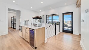 Eine moderne Küche mit integriertem Geschirrspüler, einer Kaffeemaschine und einem großen Fenster mit Blick ins Freie.