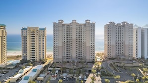 A high-rise hotel with multiple floors, a central courtyard, and a view of the beach. - Indigo East 1502 (Pensacola)