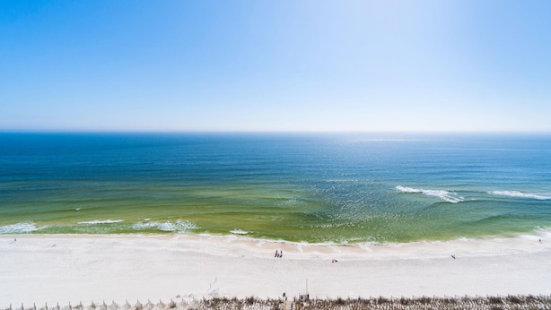 A beach with clear blue water and a sandy shore. - Indigo East 1502 (Pensacola)