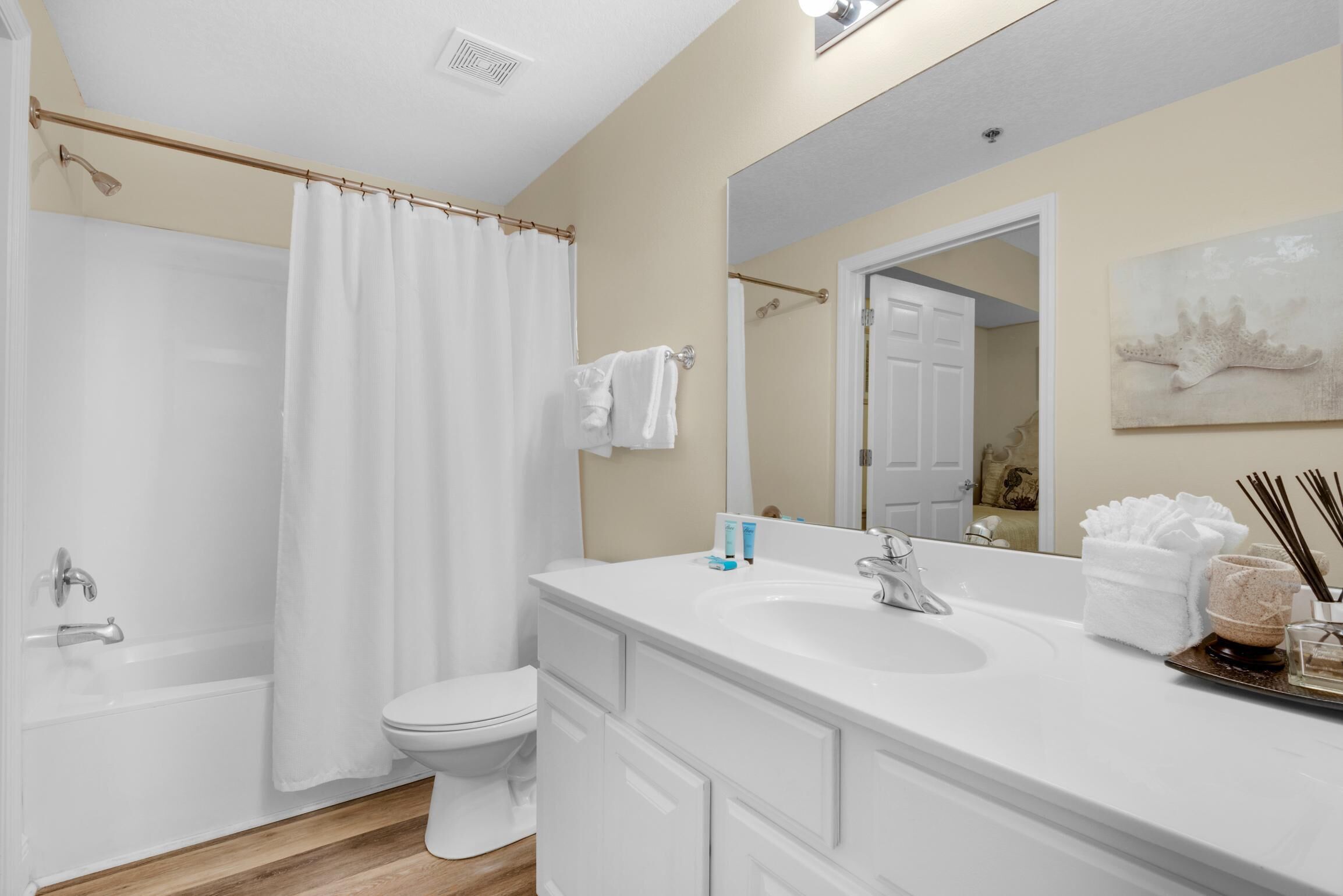 A bathroom with a bathtub, toilet, and a large mirror.
