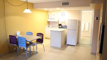 A compact kitchen with a dining area, featuring a microwave, refrigerator, and a small island.