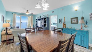 A spacious living area with a wooden dining table, blue walls, and a view of the ocean. - Ariel Dunes I 2202 (Miramar Beach)
