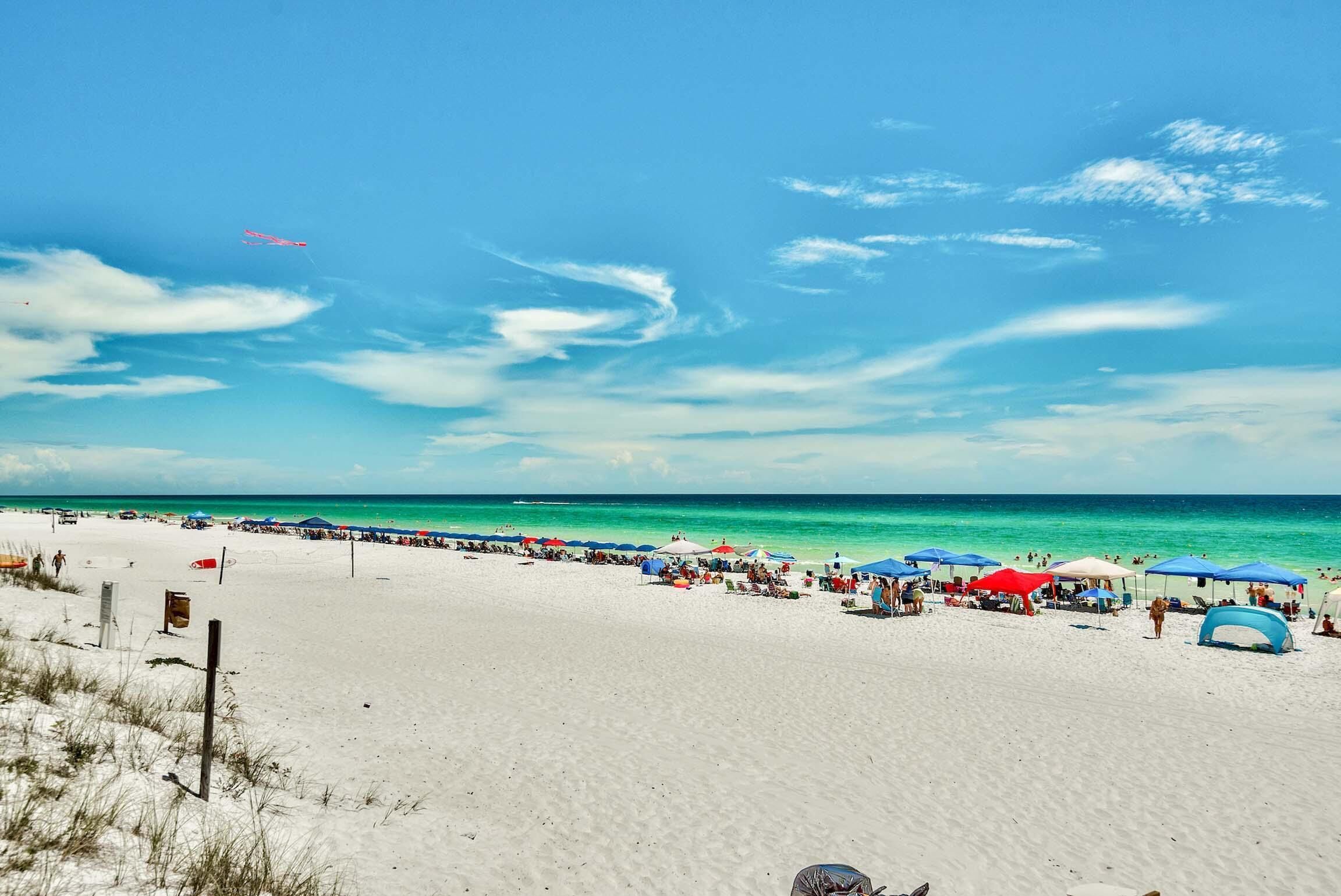 A beach with white sand, clear turquoise water, and a clear sky.