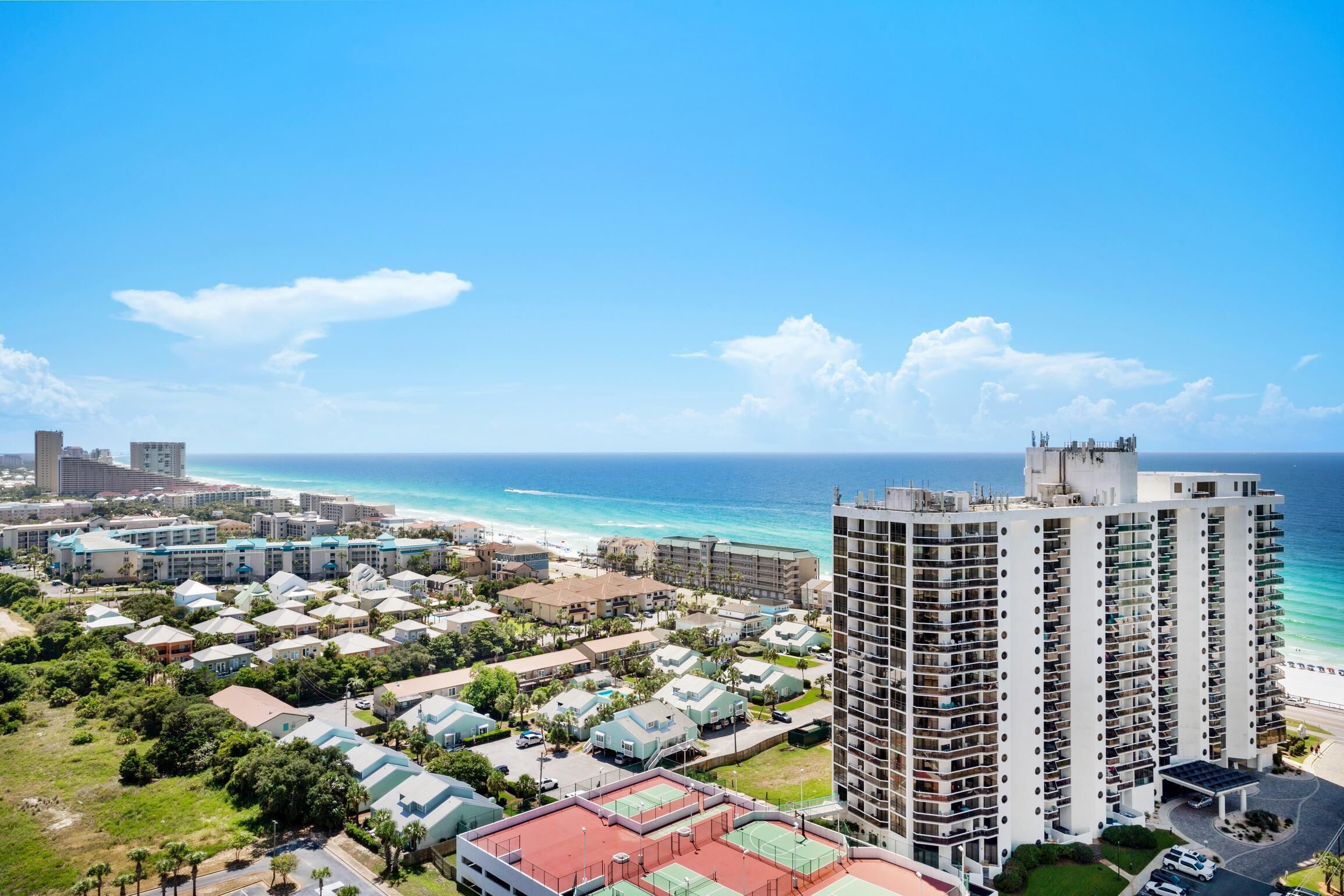 A high-rise hotel with multiple balconies overlooking a beach and ocean.