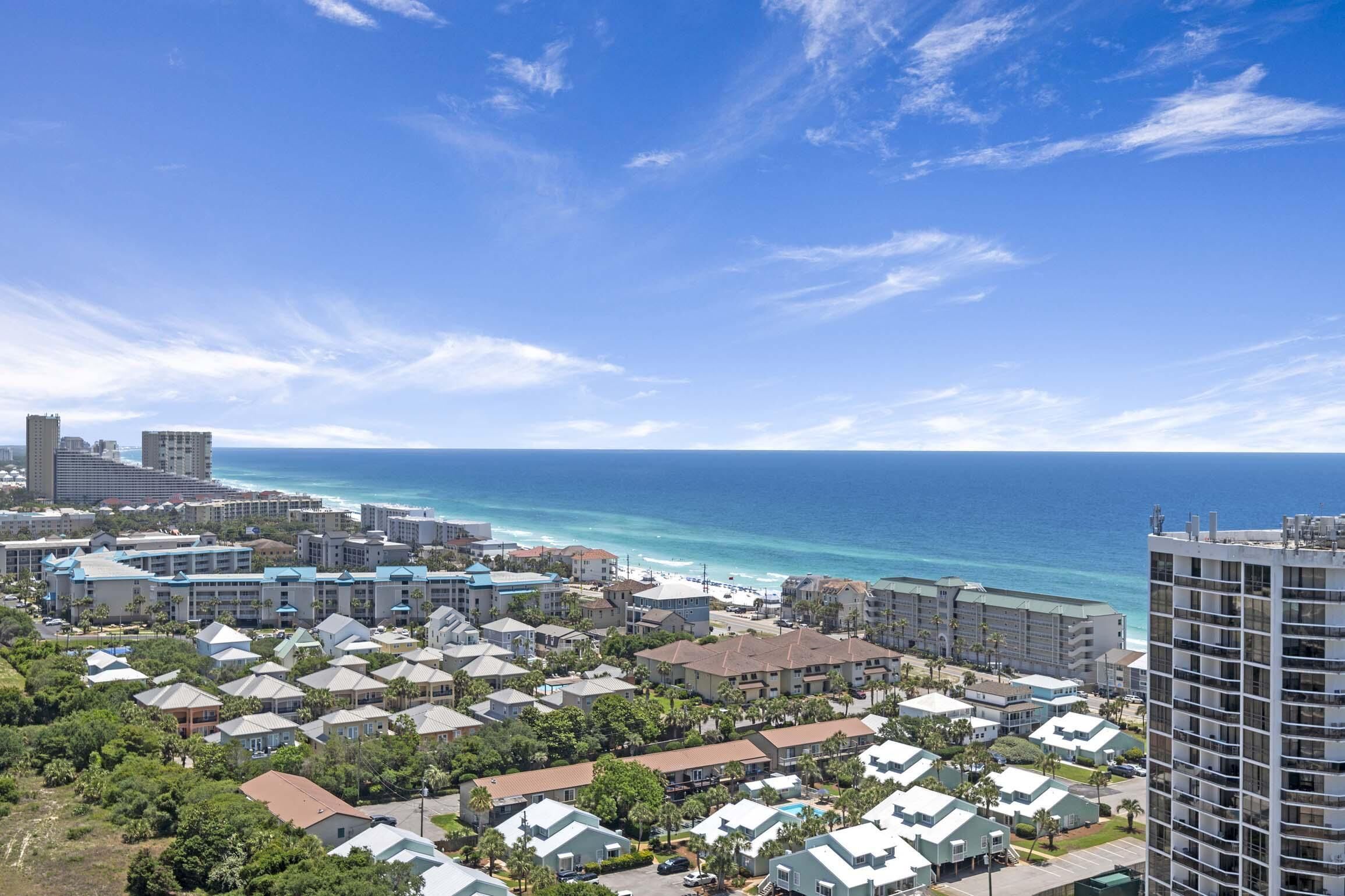 A coastal resort area with multiple buildings, including a tall hotel and smaller residential-style structures.