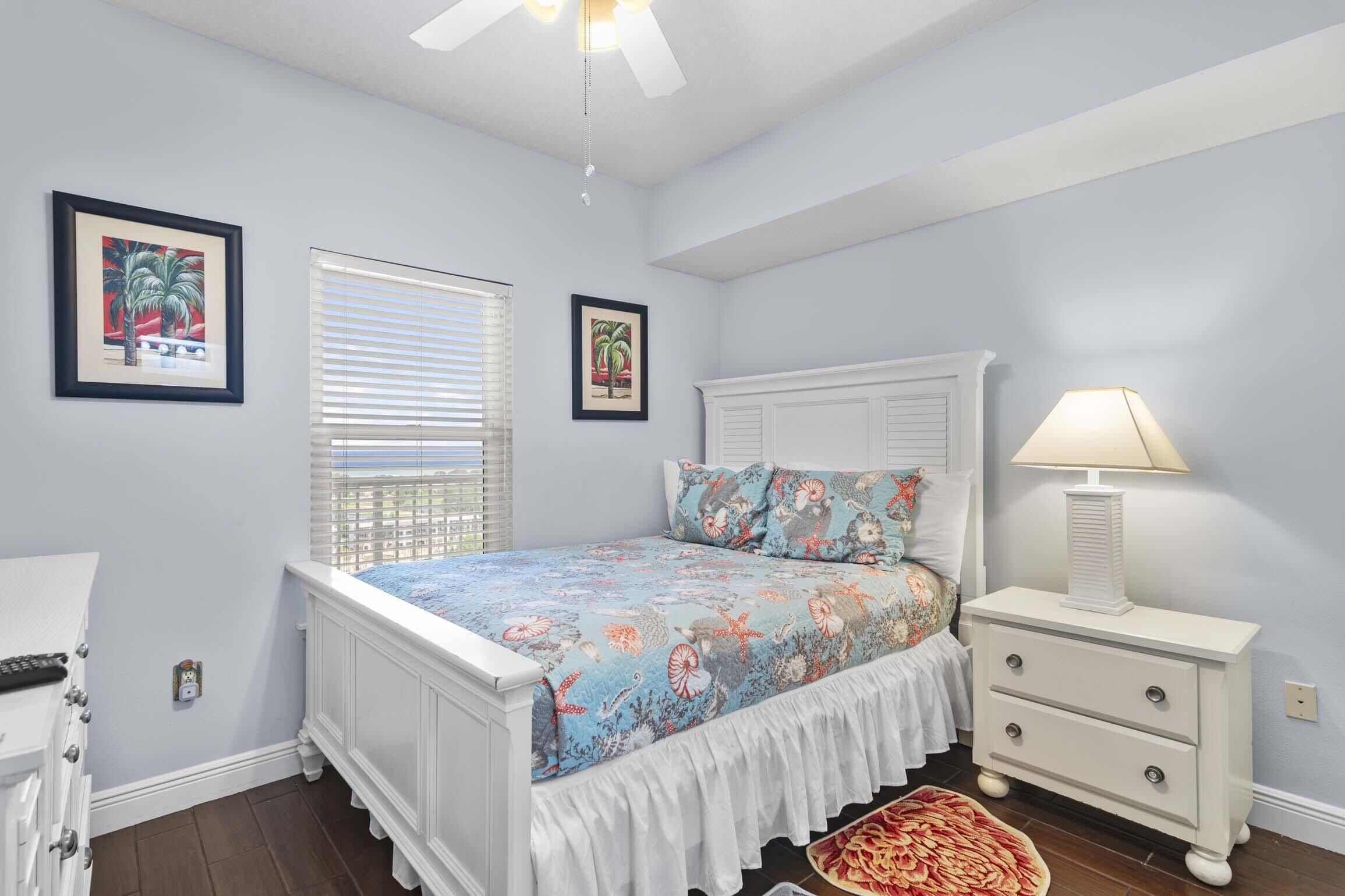 A bedroom with a bed, nightstand, lamp, and two framed pictures on the wall.