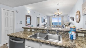 A kitchen with granite countertops, stainless steel sink, and a view to the outside. - Ariel Dunes I 2009 (Miramar Beach)