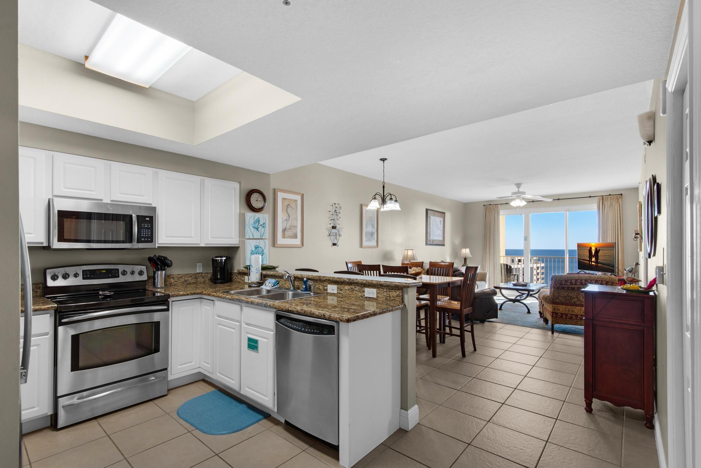 Eine moderne Küche mit Edelstahlgeräten, eine Essecke mit Blick und ein Wohnbereich mit Deckenventilator.