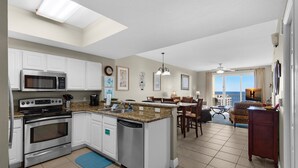 A modern kitchen with stainless steel appliances, a dining area with a view, and a living space with a ceiling fan. - Ariel Dunes I 2008 (Miramar Beach)