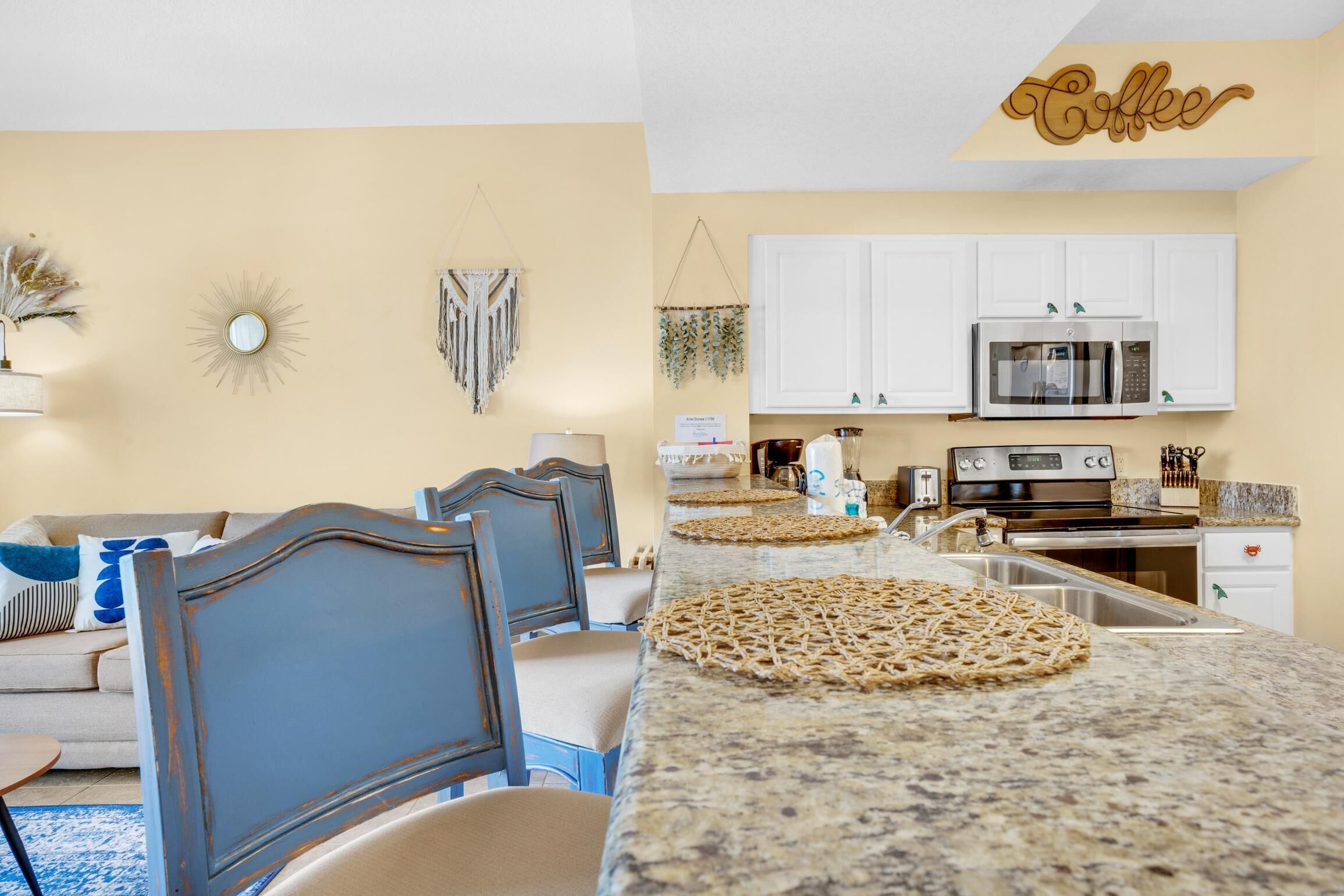 A modern kitchen with white cabinets, a microwave, and a coffee sign.