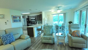A spacious living area with a sofa, armchairs, a dining table, and a kitchen in the background. - Waterfront in Historic Rock Hall, overlooking the main harbor and Chesapeake Bay (Rock Hall)