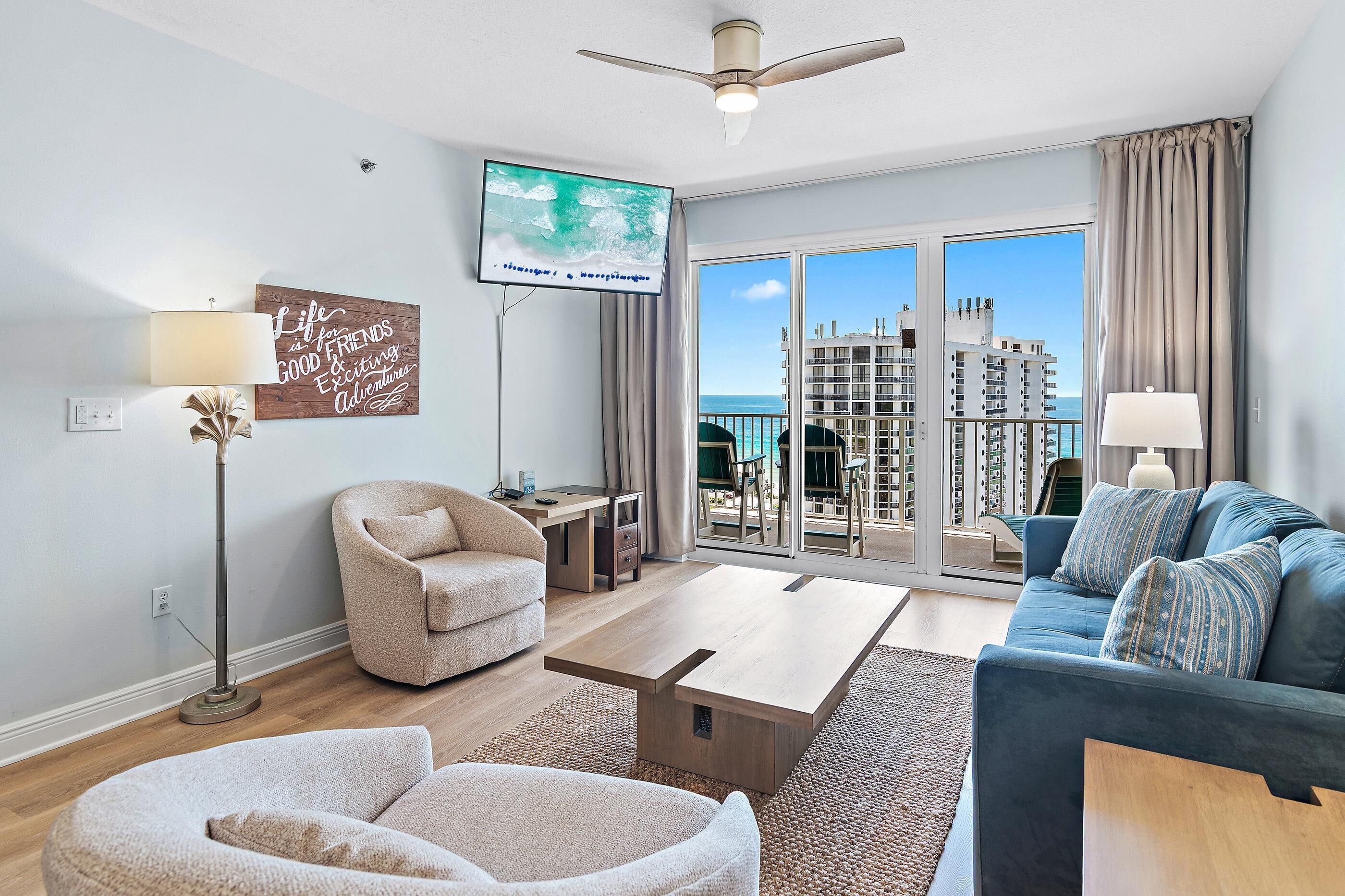 A modern living room with a sofa, armchair, coffee table, and a TV mounted on the wall.