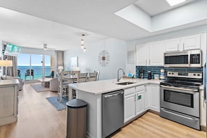 A modern kitchen with stainless steel appliances, a dining area with a view, and a balcony. - Ariel Dunes I 1403 (Miramar Beach)