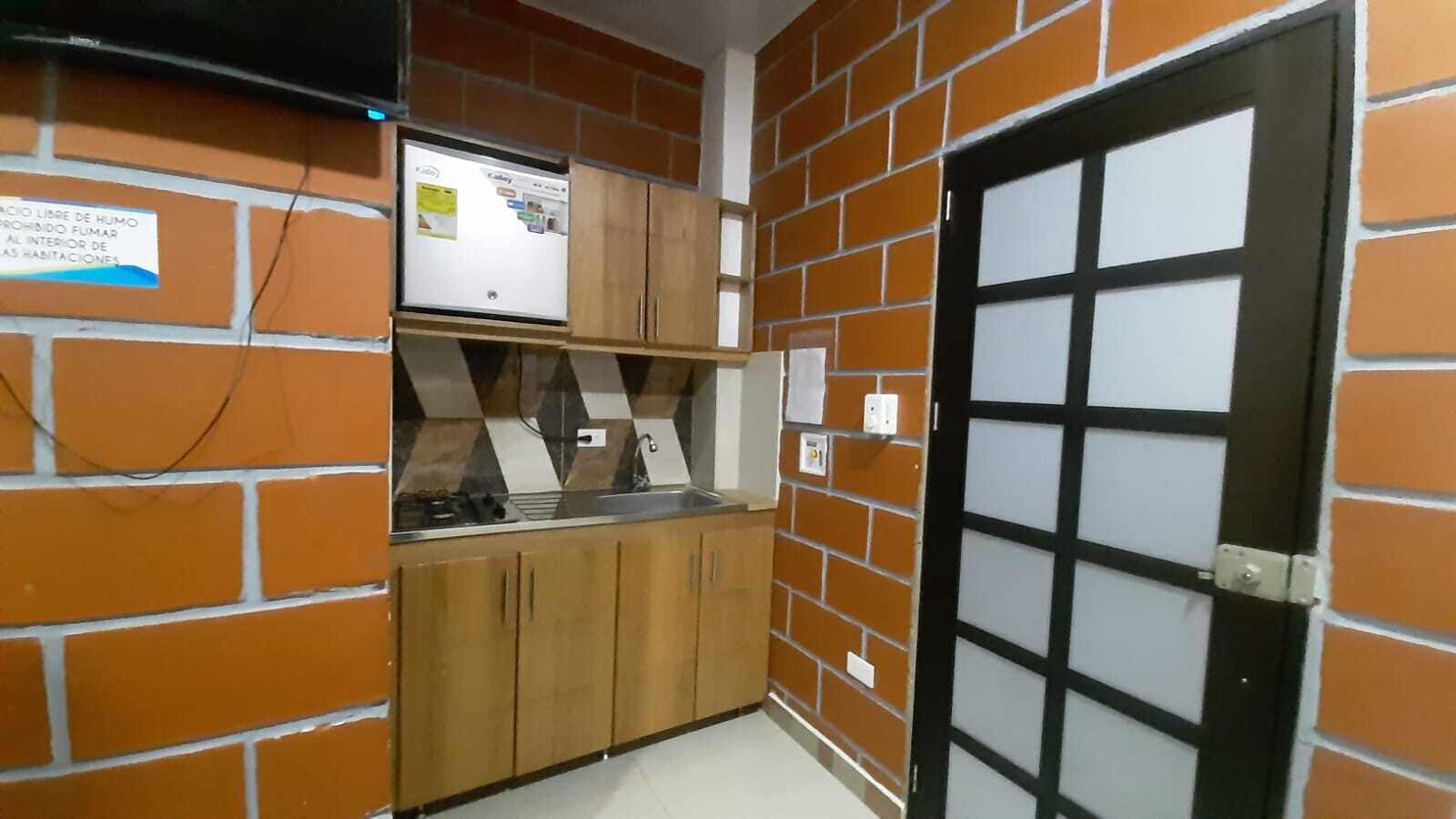 A kitchen with wooden cabinets, a built-in microwave, and a black-framed door.