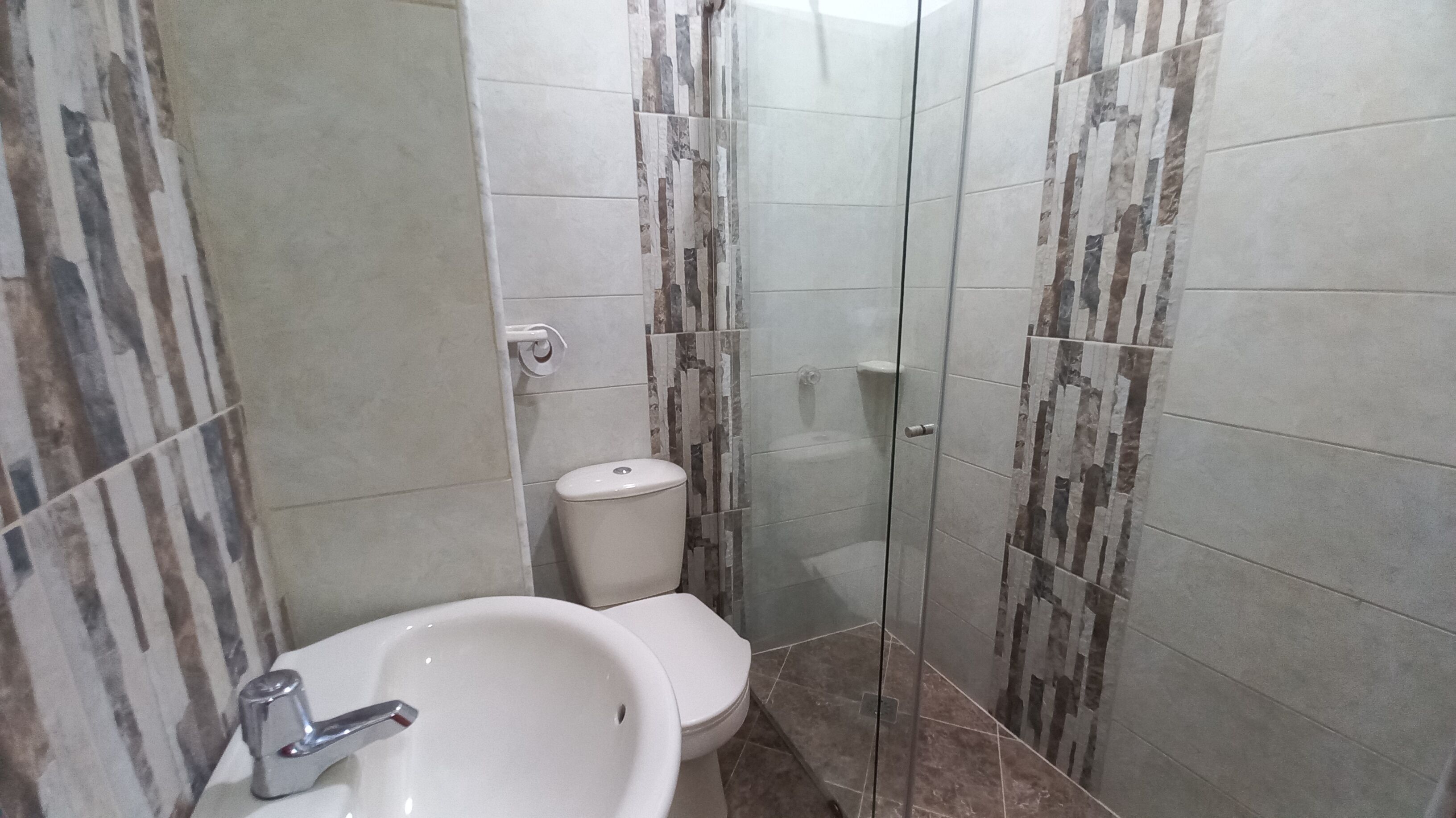 A bathroom with a sink, toilet, and glass shower enclosure.