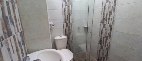A bathroom with a sink, toilet, and glass shower enclosure.