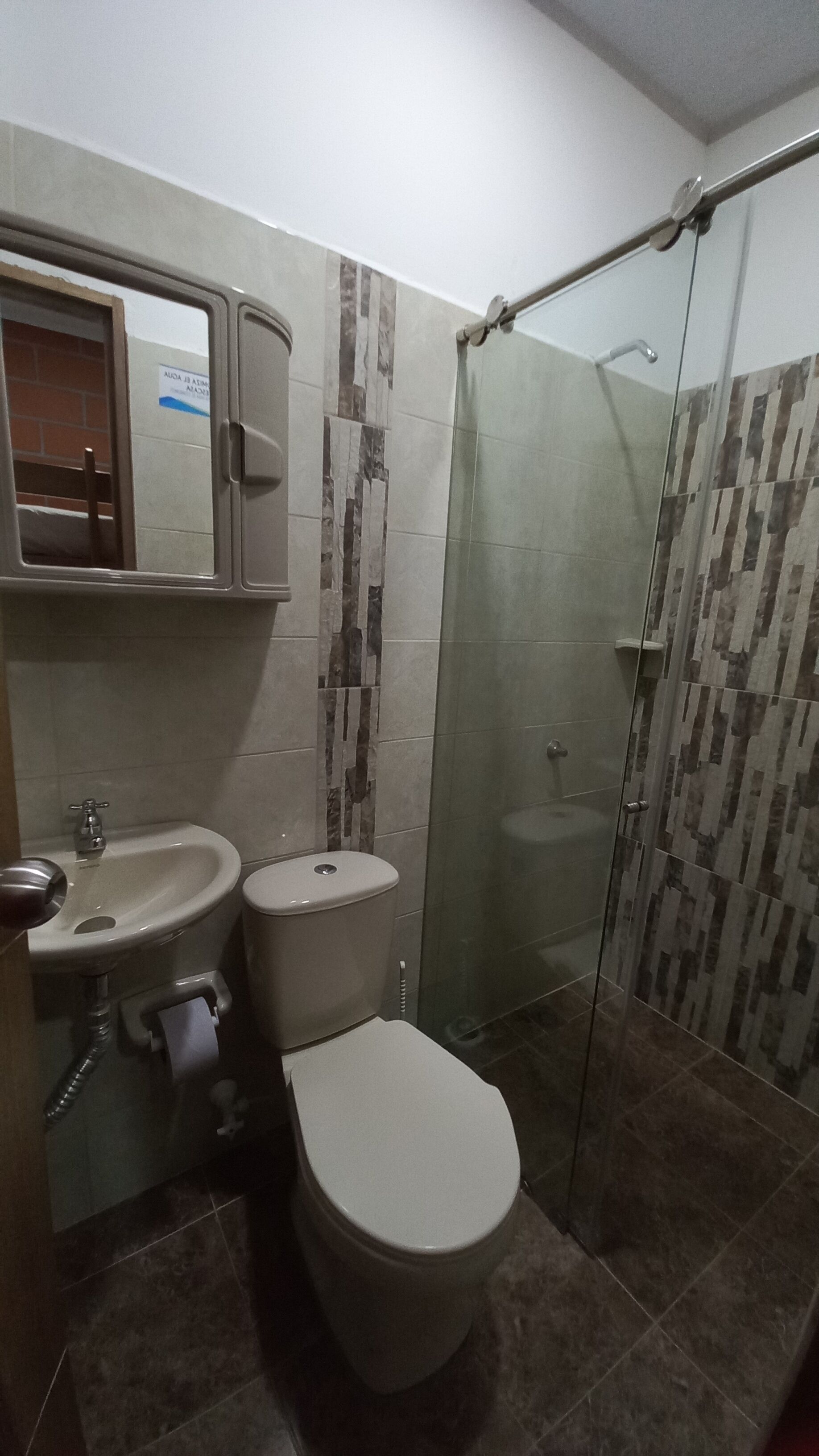 A bathroom with a toilet, sink, and shower area.