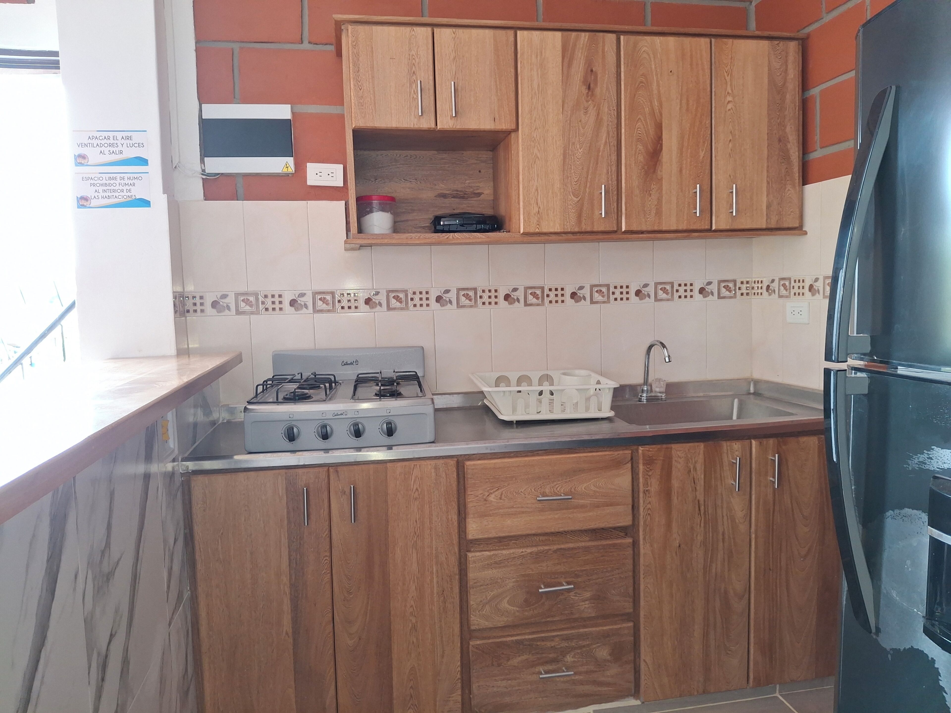 A kitchen with wooden cabinets, a gas stove, a sink, and a refrigerator.