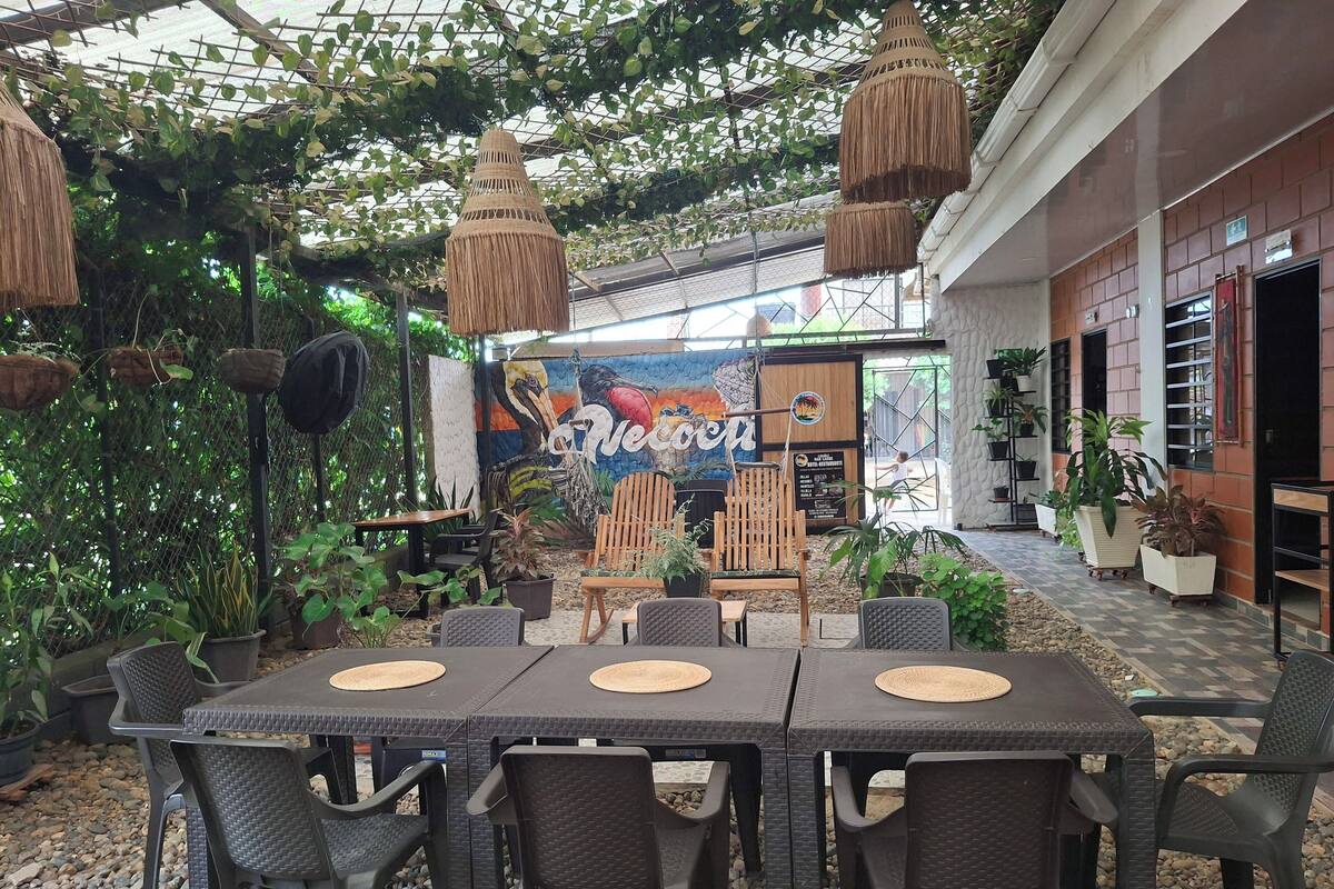 An outdoor dining area with a thatched roof, wicker furniture, and hanging lamps.