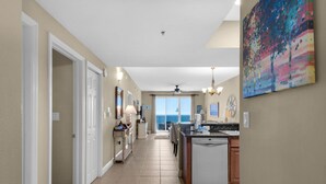 A spacious kitchen with a dishwasher, a dining area with a chandelier, and a view to the outside. - Ariel Dunes I 1307 (Miramar Beach)