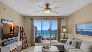 A living room with a large TV, a ceiling fan, a balcony with a view of the ocean, and a sofa. - Ariel Dunes I 1307 (Miramar Beach)
