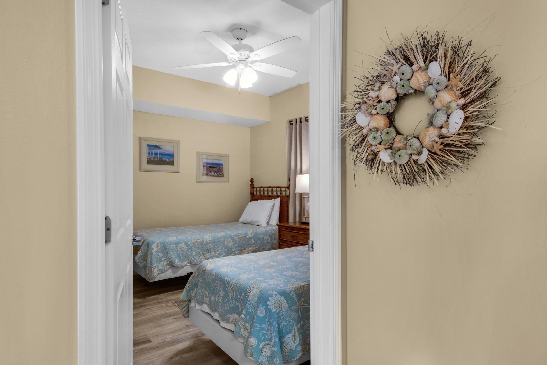 Un dormitorio con dos camas, un ventilador de techo y un adorno decorativo en la pared.