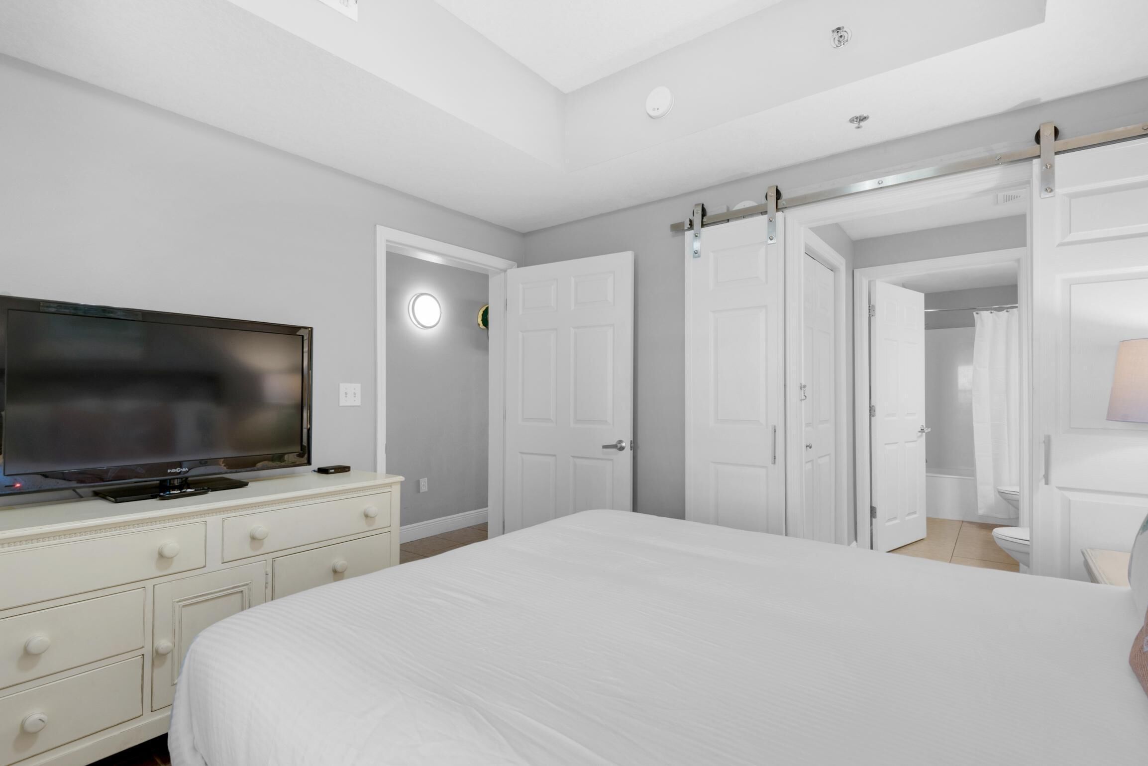 A bedroom with a bed, a TV, a dresser, and a walk-in closet.