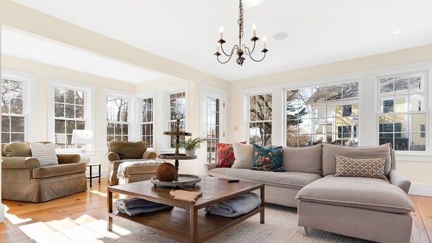A spacious living room with large windows, a chandelier, and a cozy seating area. - Picturesque Home with Harbor Views! (Kennebunkport)