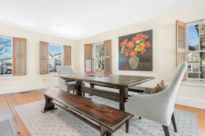 Un área de comedor con una mesa de madera, bancos y una silla gris.