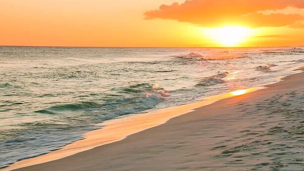 Una playa con olas y un atardecer.