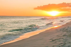 Una playa con olas y un atardecer.