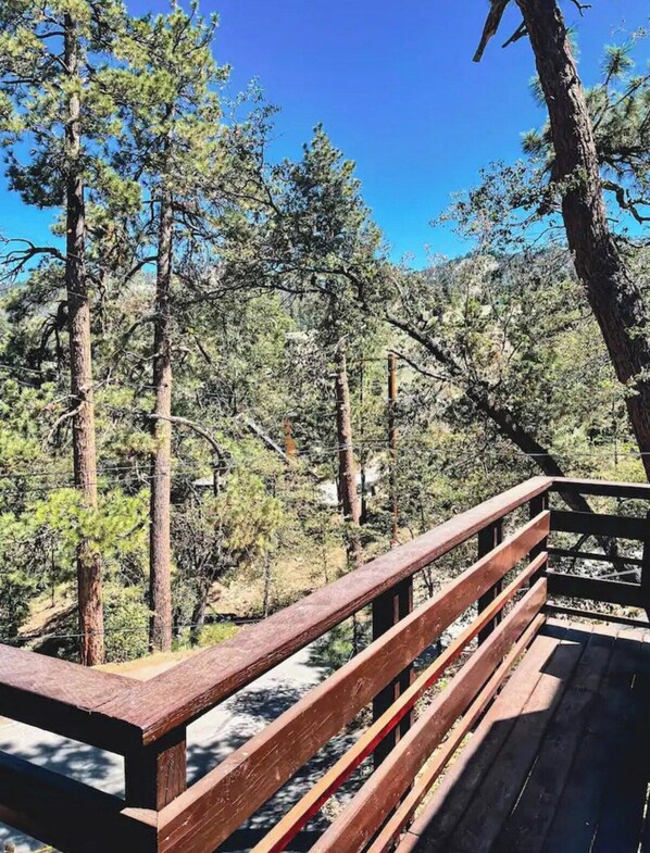 A wooden deck with railings overlooking a forested area.