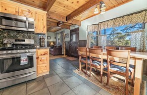 A kitchen with wooden cabinets, a stove, and a dining area with chairs and a table.